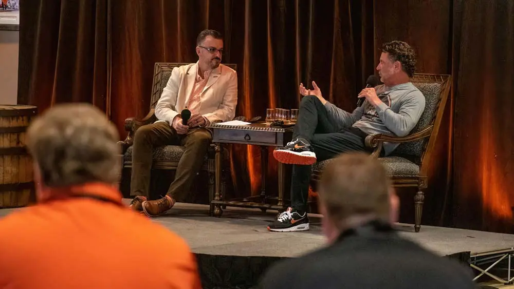two men sitting in chairs talking